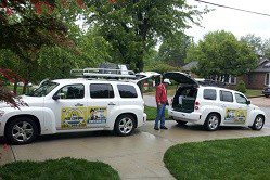 Two white suvs parked in front of a house.